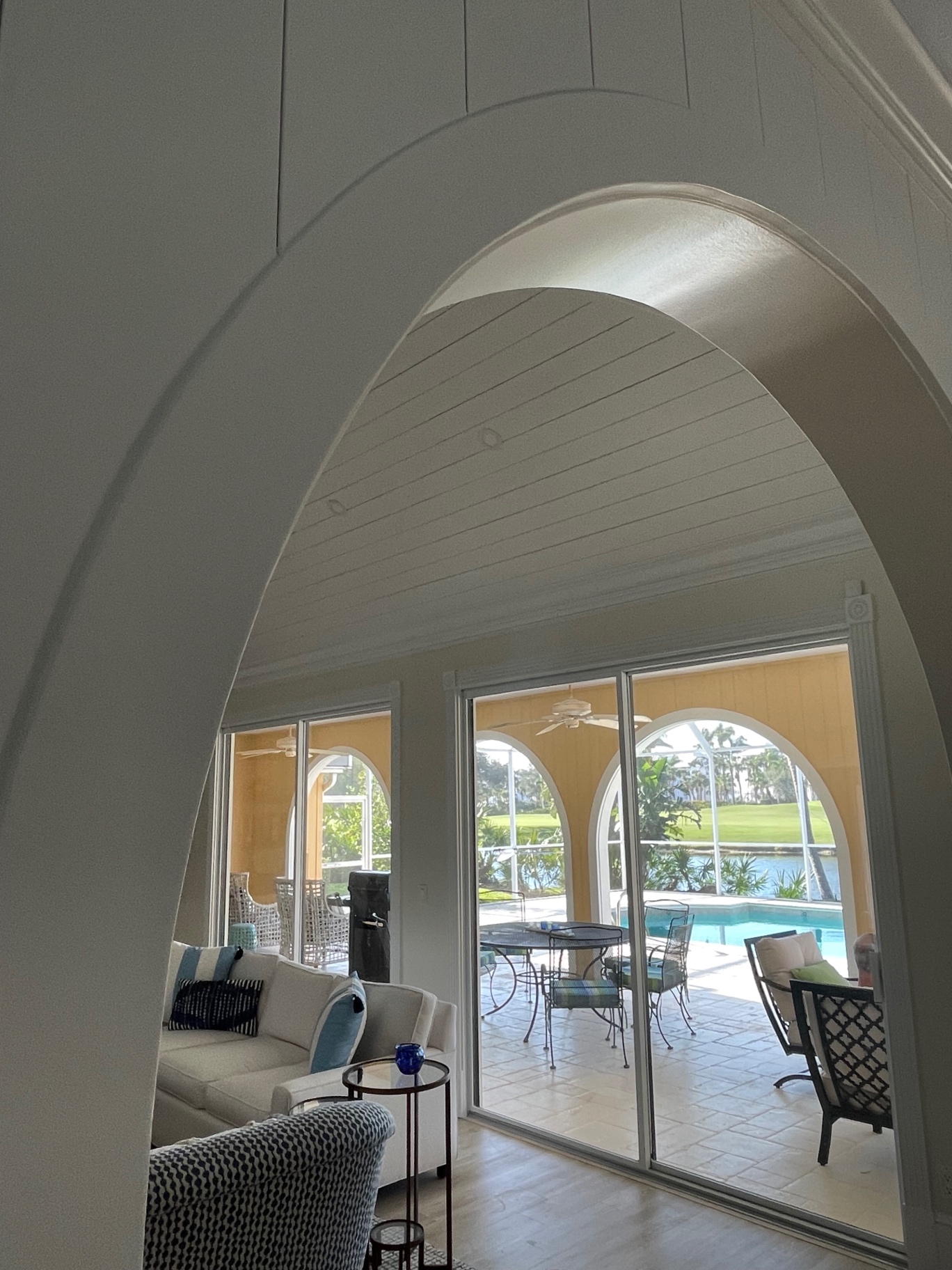 Renovated arched opening framing a pool and lanai view in a Southwest Florida home