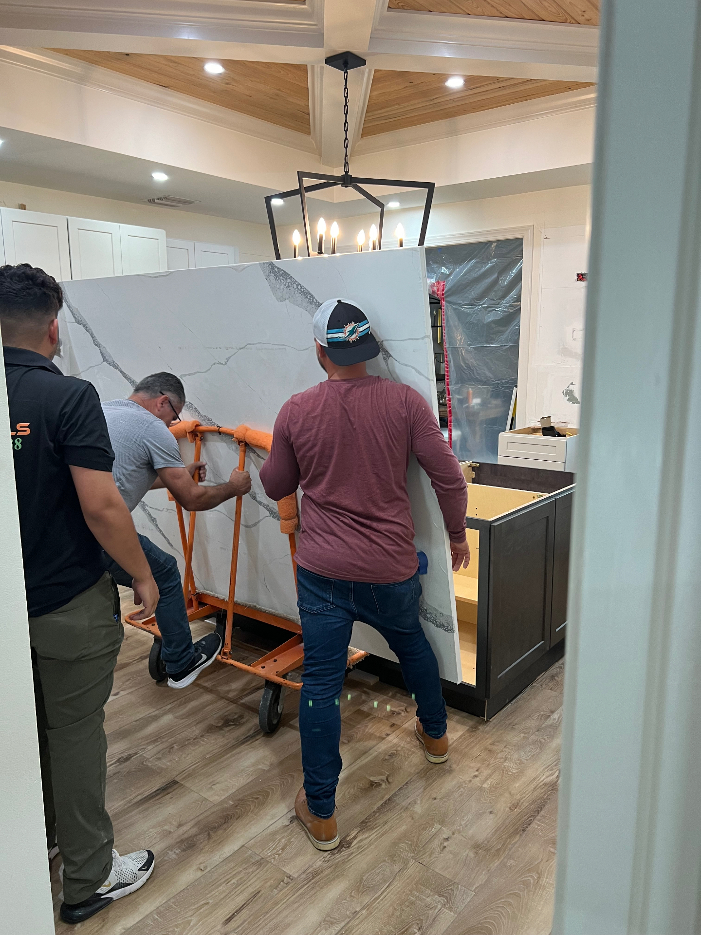 Crew installing a large calacatta quartz countertop slab on a kitchen island during a Naples renovation