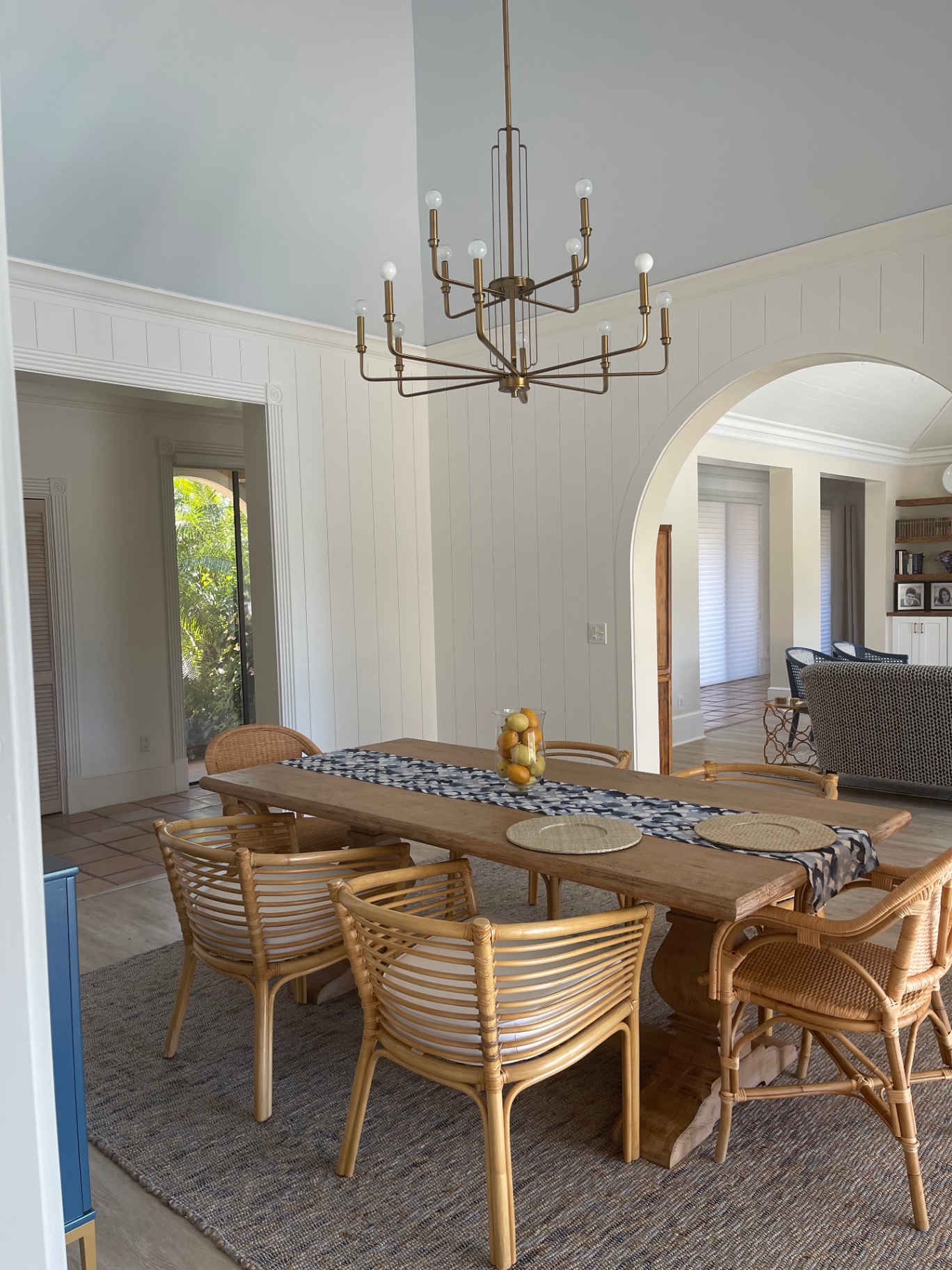 Dining room renovation with vertical shiplap walls, brass chandelier, and arched passage to the great room