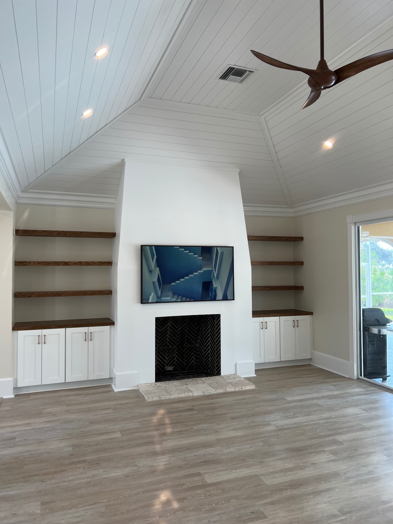 Renovated great room with plaster fireplace surround, herringbone firebox, and white oak floating shelves
